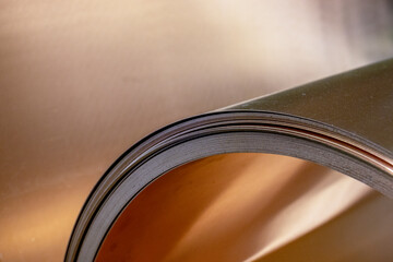 Copper sheet twisted into a roll. Curved copper sheet of various shapes. Reflections on sheets of...