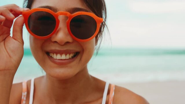 Playful asian woman in orange sunglasses looking to camera.
