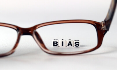 The concept of biased views judged by appearances. Business concept with white cube arranged in the word  ’BIAS' and glasses.
 - obrazy, fototapety, plakaty