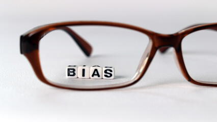 The concept of biased views judged by appearances. Business concept with white cube arranged in the word  &rsquo;BIAS' and glasses.
