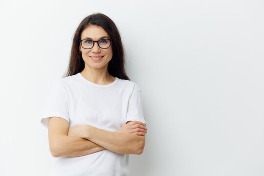  woman with long hair posing in glasses, in a T-shirt with arms crossed on her chest smiling pleasantly at the camera. Horizontal photo on a light background with empty space for advertising text