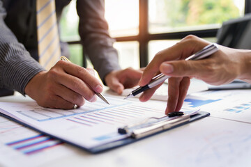 Two confident executive business colleagues meeting and discussing ideas of the project about company offers, they are pointing at a document and giving explanations, team successful business people.