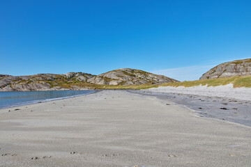 Sand on an empty beach with blue sky copy space. Beautiful landscape of a scenic ocean coastline with rocky Mountains or hills in the horizon on a clear summer day with copyspace