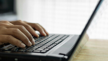 Closeup man hands typing on a computer keyboard, businessman or student using laptop at home, online learning, internet marketing, working from home, office workplace, freelance concept