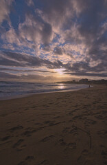 puesta de sol contra el sol en la playa con nubes en el horizonte