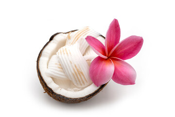 Half cut coconut and frangipani flower on white.