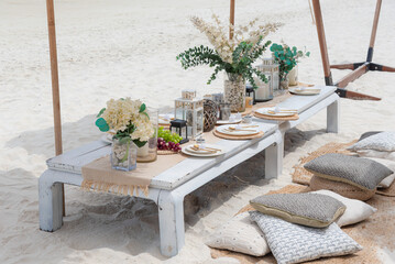 Table set for dinner in the white wooden table on the beach for chilling and relaxation, romantic scene