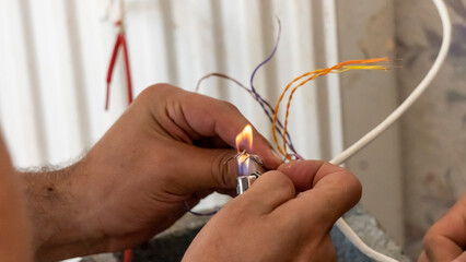 Electrician repairing an electrical installation, using a lighter, close-up