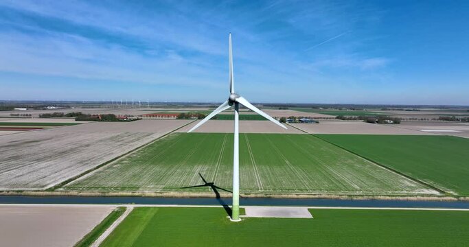 Flat Dutch landscape with water canal and wind turbines.
