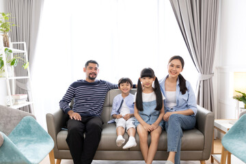 Portrait of asian family mother father and kids at home on sofa in living room.happy family concept.