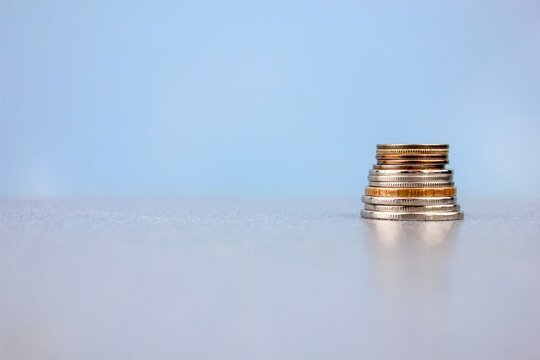 Money iron coins on a blue background close-up with space for text, copy space. A hand puts coins, money on a bright background.
