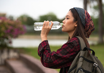 Beautiful Asian woman drinking clean water from plastic bottles.