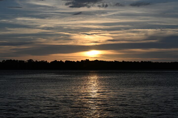 The sun sets across the river on a peaceful evening
