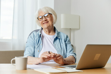 a happy, laughing woman is sitting at her desk with a laptop and smiling broadly at the camera