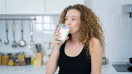 curly hair woman drinking milk at kitchen