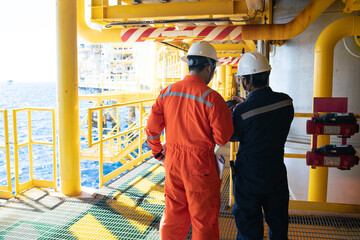 Male workers inspect long steel pipes and pipe elbows in oil and gas stations between oil and gas...