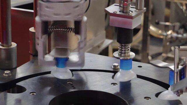Bottling machine putting on caps on plastic alcohol bottle containers
