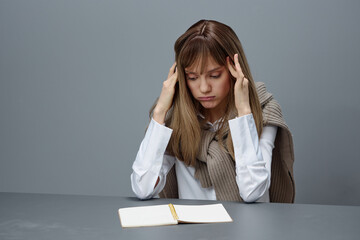 Sad tired young blonde student lady freelancer in warm sweater touch head both hands sitting at...