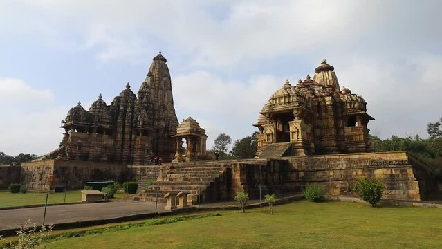 A wide-angle view of Khajuraho&rsquo;s grand temple reveals intricate carvings, soaring spires, and royal symmetry, set amidst lush green gardens&mdash;an exquisite blend of divine artistry, architecture, and ser