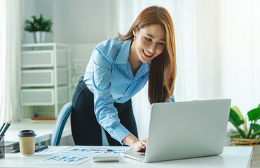 Business Woman standing working with laptop working on desk in modern office