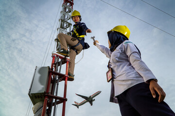 Badung, Bali, Dec 8th 2020: In a clearly day, 2 female technical workers repairing communication equipment at the airport. One of them is wearing a hijab