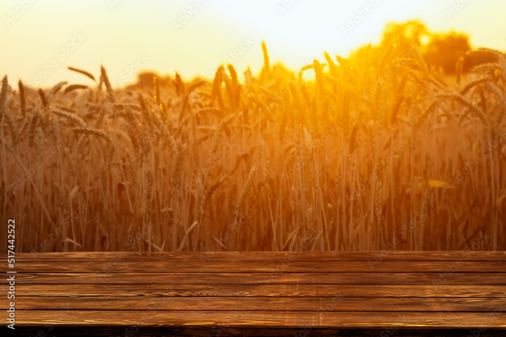 Wall mural wooden empty table and golden ripe wheat field on sunset as background