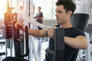 Handsome man lowering weight of fitness machine and working out in the fitness gym