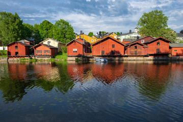 Fototapeta na wymiar Ancient red barns on the banks of the Porvoоnjoki River on a June afternoon. Symbol of the city of Porvoo, Finland