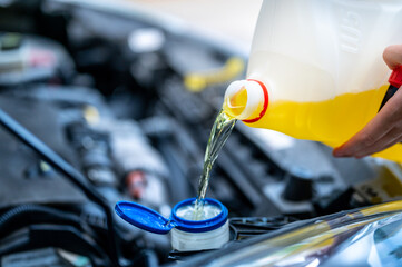 Pouring antifreeze. Filling a windshield washer tank with an antifreeze in summer hot weather.