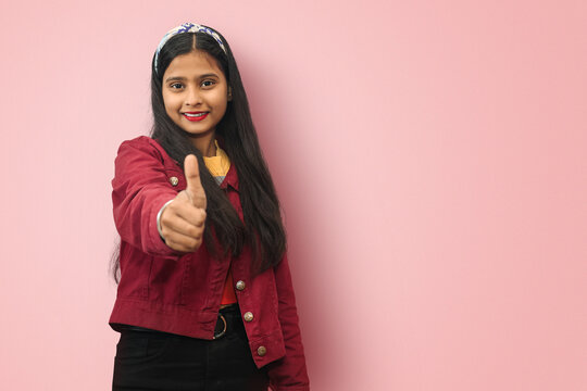 Smiling Young Indian Asian Satisfied successful girl posing isolated with thumbs up gesture. Mock up copy space.