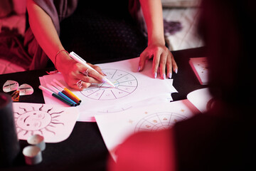 Closeup image of female astrologer drawing natal card for female client