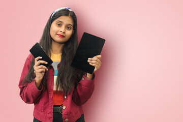 Naklejka premium Young Indian Asian teenage smiling cheerful cute girl posing isolated displaying mobile phone and tablet with mockup copy space.