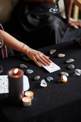 Young woman using tarot cards and rune stones for divination practice at home