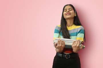 Excited young indian asian girl student posing islolated holding textbooks with love fond of...