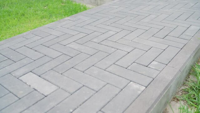 Gray tiles on the sidewalk in sunny weather. Paving stones. Concept of laying paving slabs and pavers. Paving stones. Concrete pavement blocks.