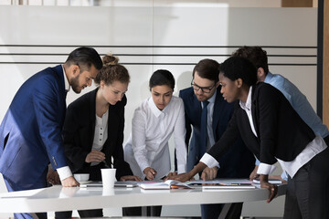 Multiethnic millennial business group of employees discussing project strategy, plan, standing at...