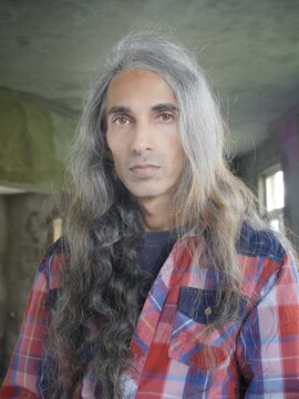 Long haired man wearing check shirt, looking at camera