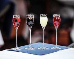 Row of assorted liqueur glasses on restaurant table - obrazy, fototapety, plakaty