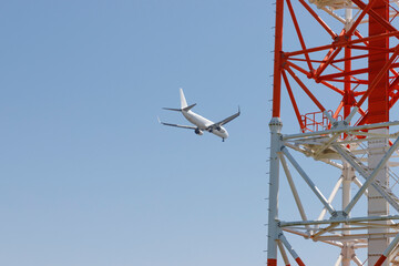 電波塔の上を通過して着陸態勢に入る飛行機