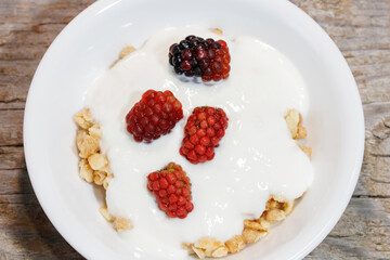 白いボウルにシリアル、ヨーグルト、赤いラズベリー