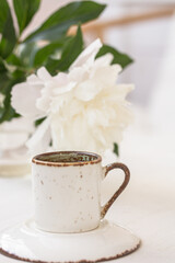White Cup of coffee or tea, white peony, on white background. Freshness concept.