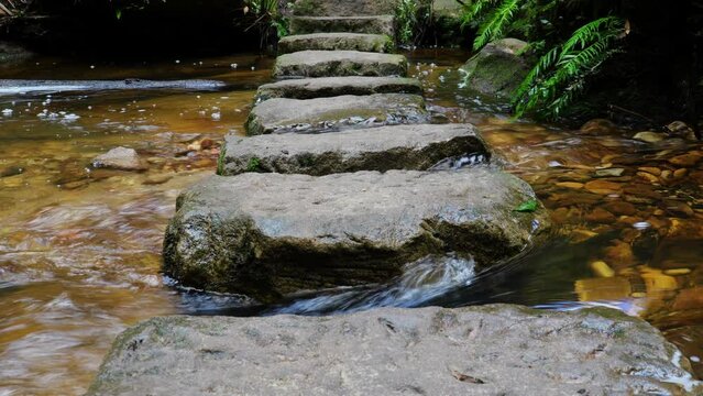 Water flowing fast around stepping stones in the grand canyon bushwalk, Blackheath, NSW, Australia