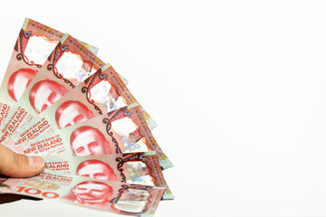 A file of New Zealand hundred dollar bills held in hand on a white background, Space for an...