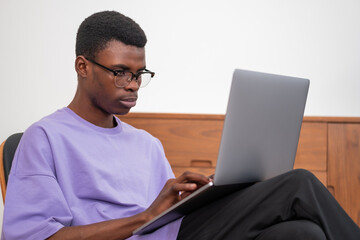 Serious African American businessman sitting working on laptop on lap