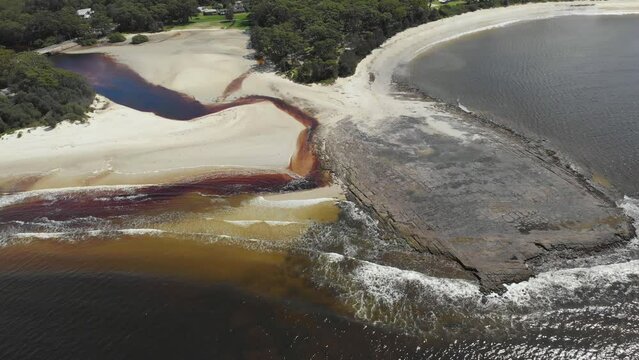 Drone video of Moona Moona Creek and Huskisson beach area after recent flooding with brown dirty water flowing into the bay