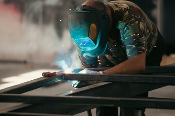 Industry worker welding iron pieces at work