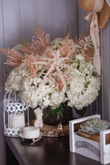 A succulent on a decorative bicycle and a bouquet of white hydrangeas and astilba. Interior in Provence style. A concept for a flower shop or home comfort and decor in the house.
