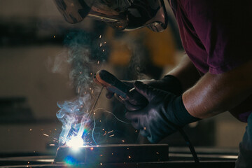 Industry worker welding iron pieces at work