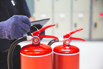 Obraz premium Fire extinguisher has hand engineer inspection checking pressure gauges to prepare fire equipment for protection and prevent in emergency case and safety or rescue and alarm system training concept.