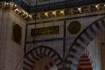 Obraz premium Interior of Suleymaniye Mosque, Quran text on green plates in mosque, beautiful wall decorations, low brightness historical Islamic building